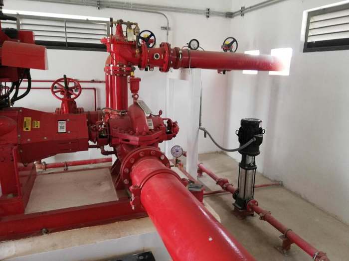 Bomba vertical con tuberías rojas dentro de un cuarto técnico