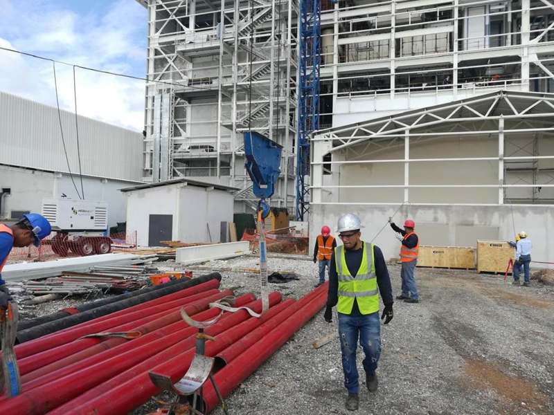Instalación de tubería roja en una obra frente a una estructura metálica